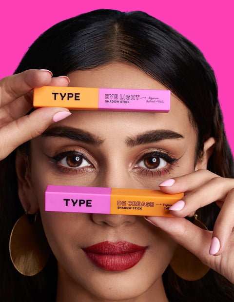 "Model showcasing Eyeshadow Combo with vibrant shadow sticks against pink background."