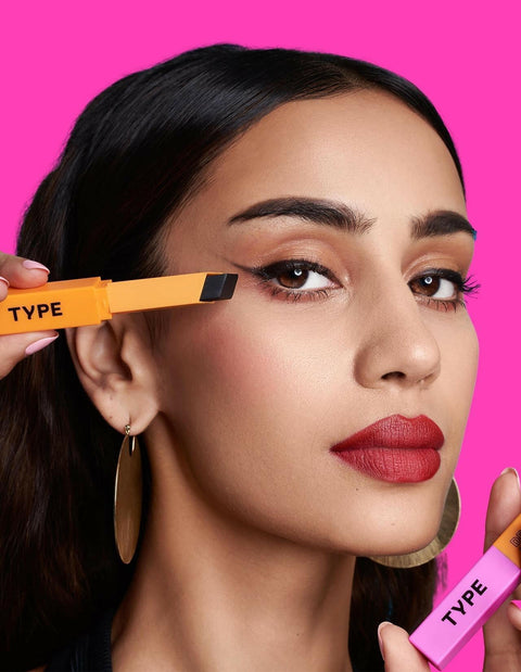 "Model applying EYE LIGHT Eyeshadow Stick against vibrant pink background."