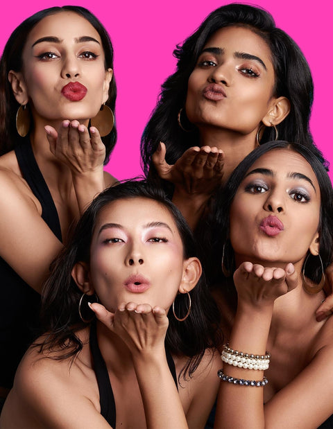 Diverse models showcasing vibrant lipstick shades in a playful pose.
